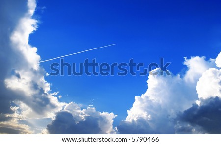 The jet plane in a stratosphere, reserves an equal white loop, the bright blue sky, the low cumulus clouds illuminated by the evening sun.