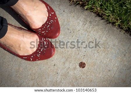 A girl in red shoes finds a penny on the sidewalk. Pick it up and you\'ll have good luck all day!