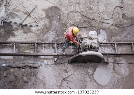 worker was incisesing the stone, He move the cutting machine along the guide rail reciprocating time and time again.