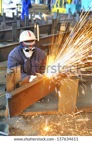 worker using torch cutter to cut through metal in factory