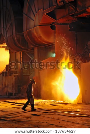 A steel worker takes a sample from oven