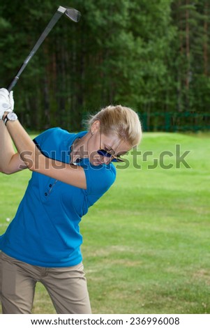 Young woman golf player on course doing golf swing,