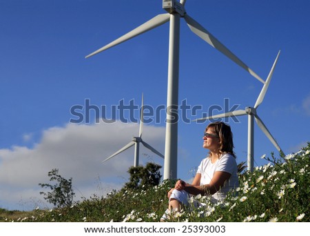 young woman dreams about the future on a wind farm beneath eolic generator