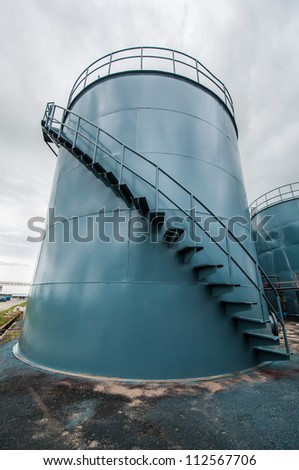 Vertical picture of  storage tanks and ladder on cloudy background
