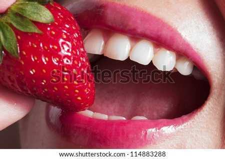 Macro close up of a beautiful female mouth eating a fresh strawberry