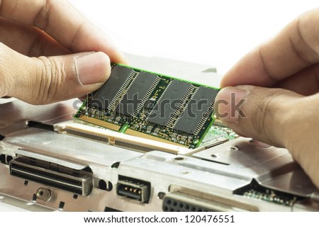 Human hand placing the RAM memory card on laptop computer motherboard