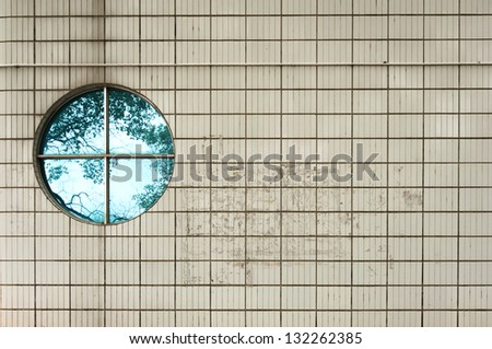 Round  vintage  window on ceramic tile wall building with tree reflection