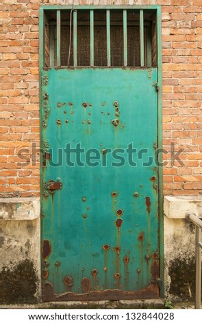 Rusty green metal door on orange brick wall