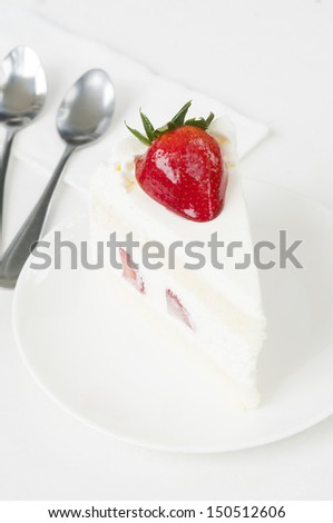 Piece of white strawberry cake with two spoon