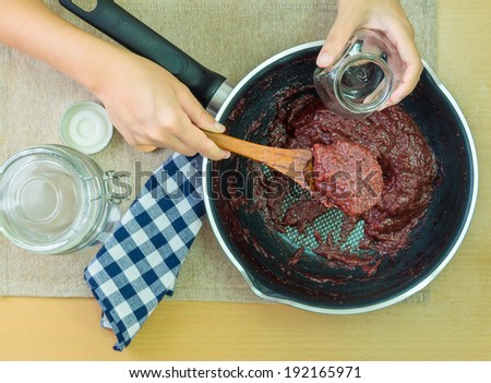 Strawberry jam making, Woman hand take cooked strawberry jam in pan to little glass jar. Filtered process photo.