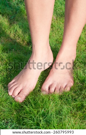Woman feet walk over green grass.