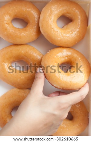 Hand picking donuts in box