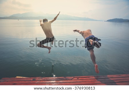Young men jumping into lake retro image processed.