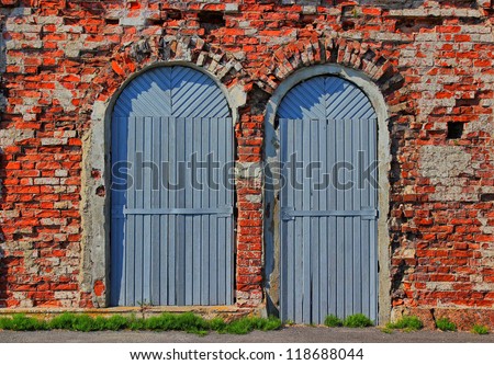 Grunge background of two arch wooden doors and red ancient bricklaying of the 18th eyelid.