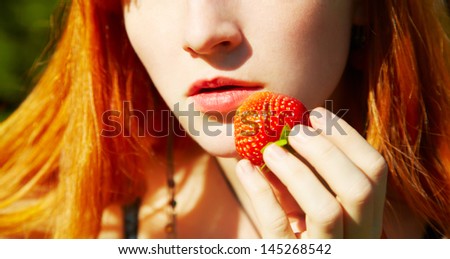 beautiful redhead girl taste a strawberry, closeup, focus on the lips