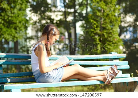 girl reading a book in the park sitting on the bench