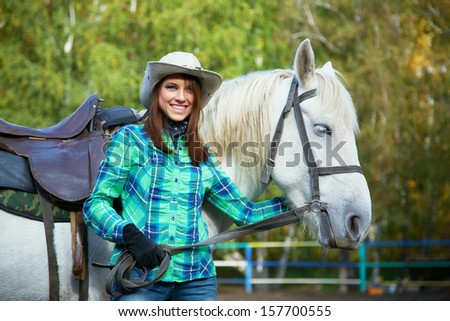 cute smiling cowgirl in a hat with a white horse