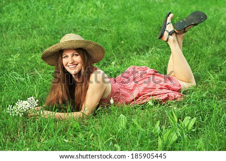 beautiful smiling dreaming woman in a hat with a bouquet of white flowers lying on the grass in the park. woman outdoors