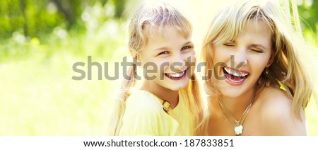hugging happy mother and daughter for a walk in the park on a light green background. banner
