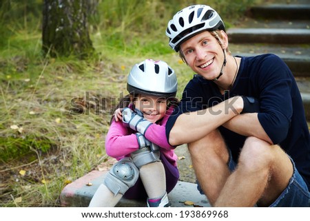 portrait of a sports dad and daughter in a helmet. Dad with his little daughter on the skates