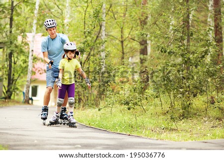 portrait of a sports dad and daughter in a helmet. Dad with his little daughter on the skates. two people rollerblade