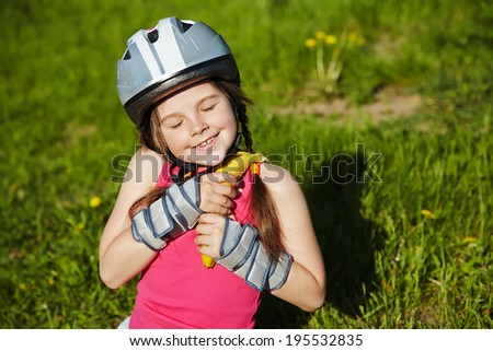 Little girl in helmet and roller skates at a park. children outdoors. sports food