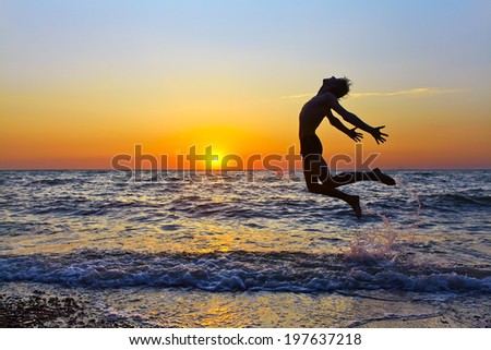 silhouette of a happy man jumping on a sunset on the sea. healthy lifestyle. freedom, inspiration and breakthrough