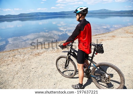 cyclist admires the scenic views of the mountain lake. man outdoors