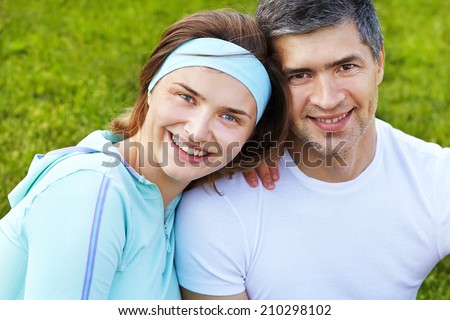 sports smiling adult couple on the background of green grass. healthy lifestyle. outdoors