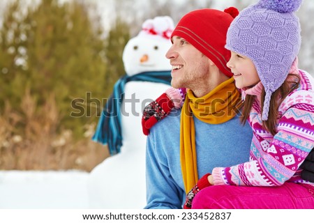 funny dad and daughter with a snowman. Family walking outdoors in winter