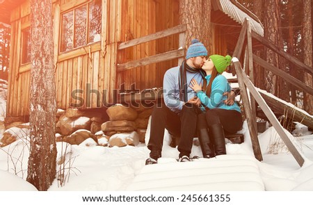 man and woman sitting on the porch of a house. young happy couple in love outdoors in the winter