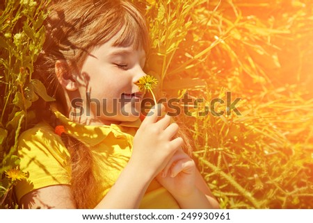 little girl sitting in the grass with dandelion in her hands. child outdoors. colorized and toned photo