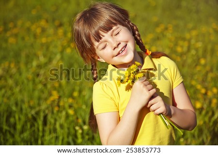 little girl sitting in the grass with dandelion in her hands. child outdoors