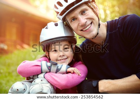 portrait of a sports dad and daughter in a helmet. Dad with his little daughter on the skates