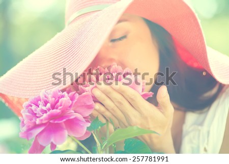 photo with artistic blurring and blur effect. special defocused effect. Vintage toning. film retro style. outdoor closeup portrait of a beautiful woman. lady in a hat in the park with flowers