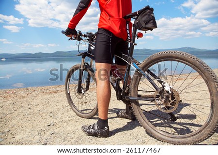 cyclist on the shore of a mountain lake. man outdoors. mountain bike