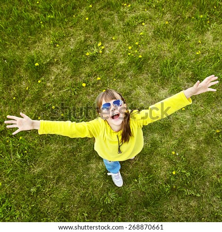 cheerful girl in sunglasses standing on the grass in the park. child outdoors. vacation in the summer park. top view