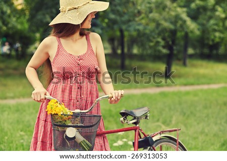 young woman in a dress and hat with a bike in a summer park. Active people. Outdoors
