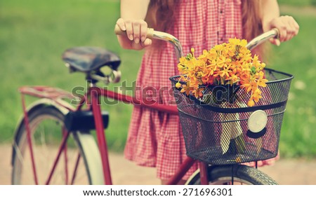 young woman with a bike in the park . flowers in a basket. Outdoors