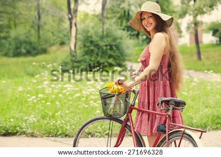 young woman in a dress and hat with a bike in a summer park. Active people. Outdoors