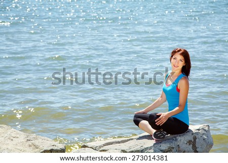 young beautiful woman meditating on the sea shore on a background of water. fitness, yoga outdoor