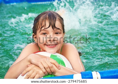 funny little girl splashing in the water in swimming pool. child outdoors