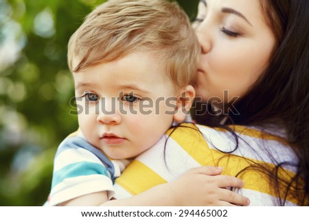 outdoor portrait of mother and son on green background. child and mom in the summer park