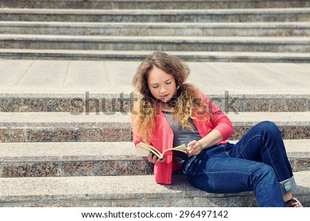 Pretty girl reading a book while sitting on the stairs.  youth lifestyle