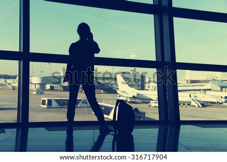 businesswoman at the airport. silhouette of a girl with mobile phone and backpack. business and travel