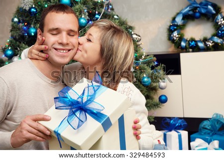young couple celebrating Christmas at home. man and woman with a gift box. New Year and xmas people