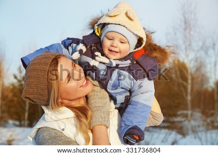 happy mother and baby in winter park. family outdoors. cheerful mommy with her child