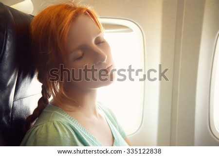 sleeping woman in the chair on board the aircraft. girl in an airplane. flight and travel