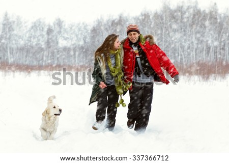 Young couple with a dog on a winter walk. man and woman with labrador outdoors