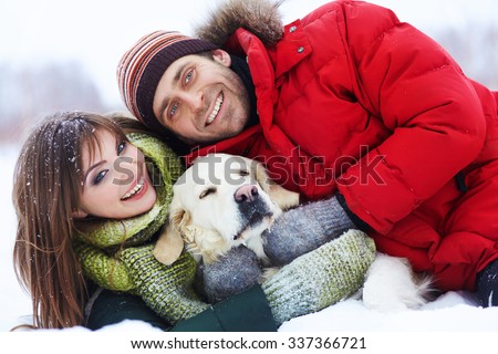 portrait of a young couple with a dog on a winter walk. man and woman with labrador outdoors